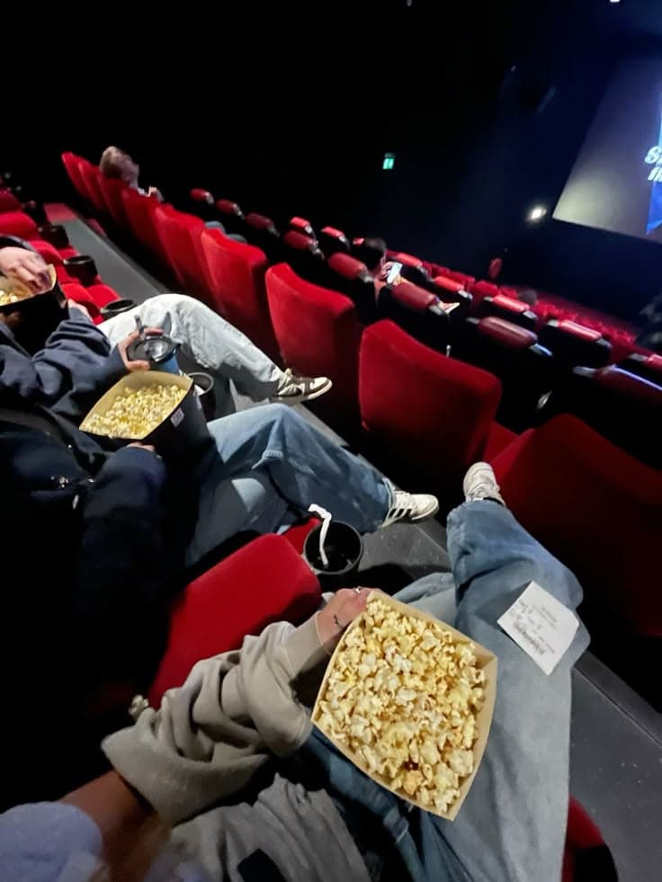 Friends with popcorn and feet up on the seats in a cinema